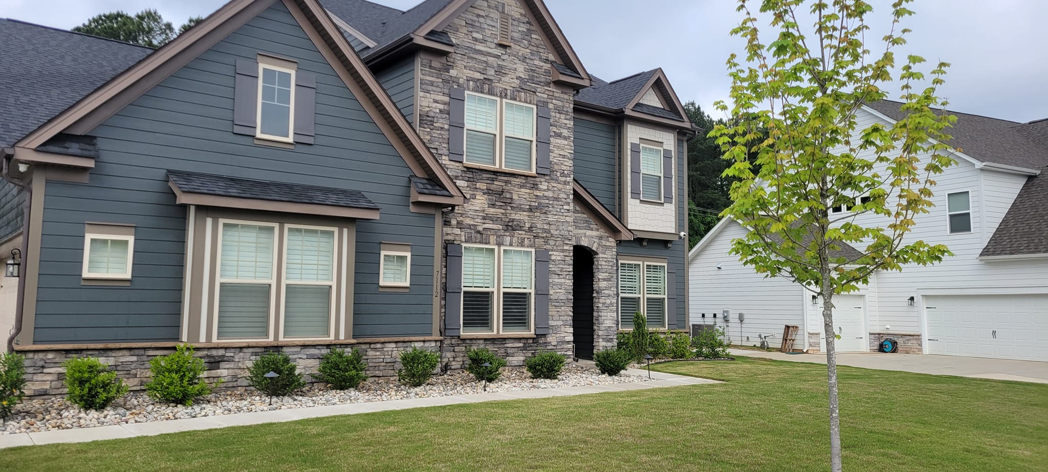Two-story home with clean siding and stone veneer exterior